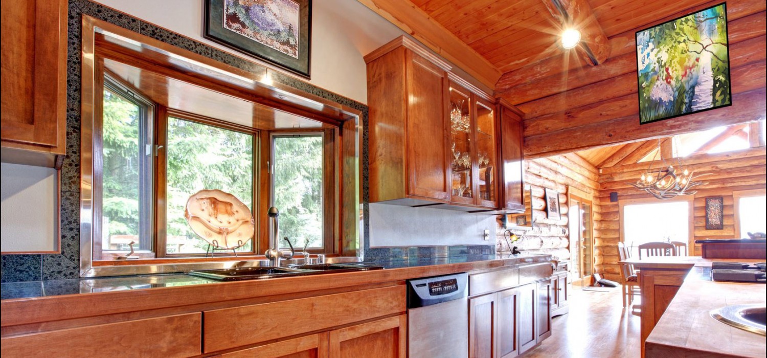Kitchen counter run with wood cabinetry and a picture window facing pines