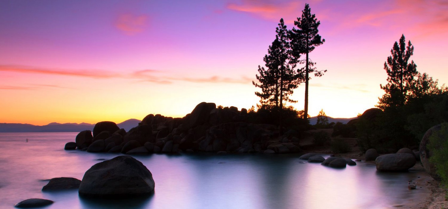 Pines and boulders silhouetted against a Lake Tahoe sunset